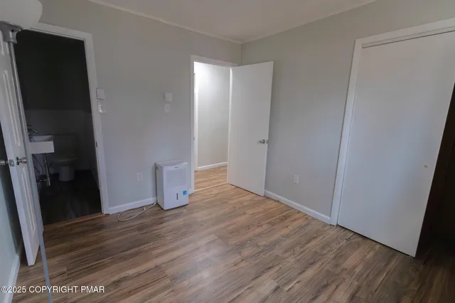 a view of an empty room with wooden floor and closet