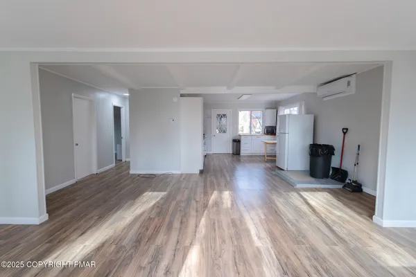 a view of a living hall with wooden floor and a kitchen