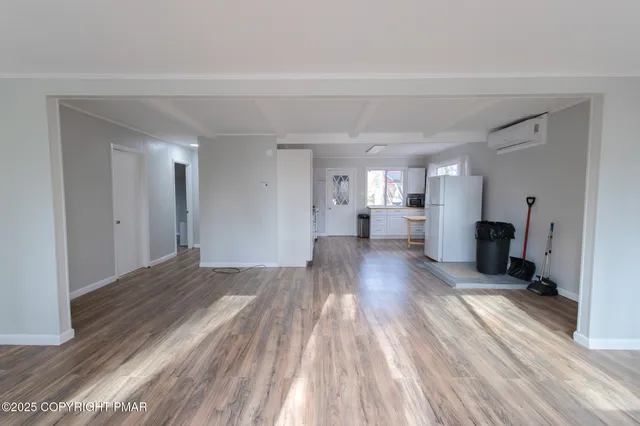 a view of a living hall with wooden floor and a kitchen