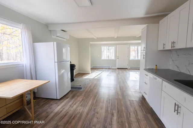 a kitchen with stainless steel appliances granite countertop a refrigerator a sink dishwasher a stove and white countertops with wooden floor