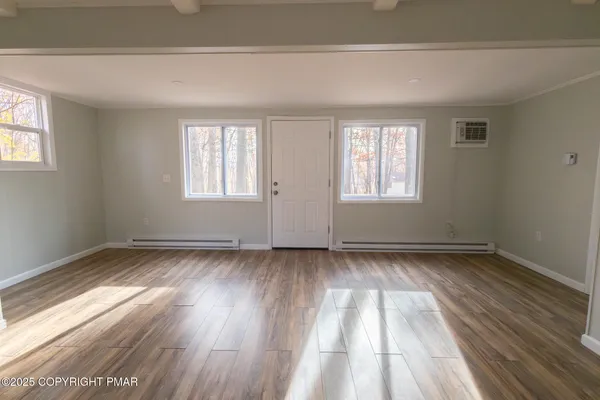 an empty room with wooden floor and windows