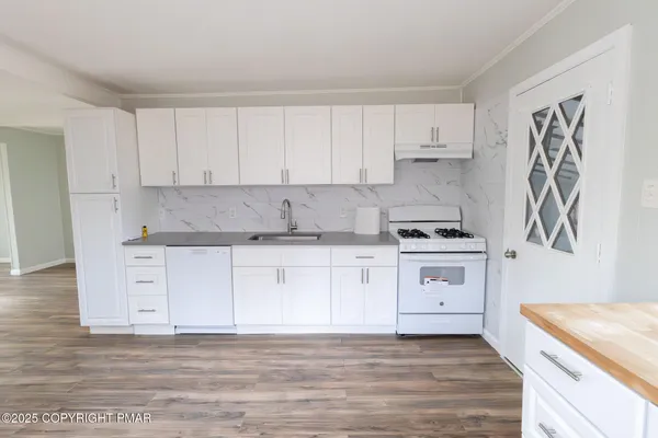 a kitchen with granite countertop white cabinets and white appliances