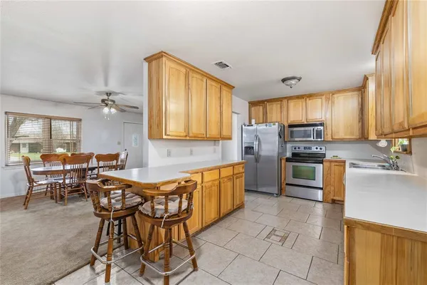 a kitchen with stainless steel appliances kitchen island granite countertop a table chairs microwave and sink