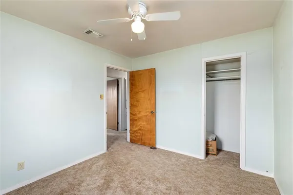 an empty room with closet and a ceiling fan