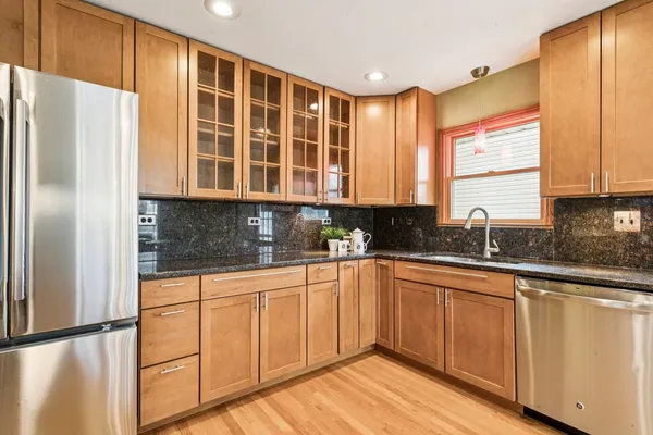 a kitchen with stainless steel appliances granite countertop a refrigerator and wooden cabinets