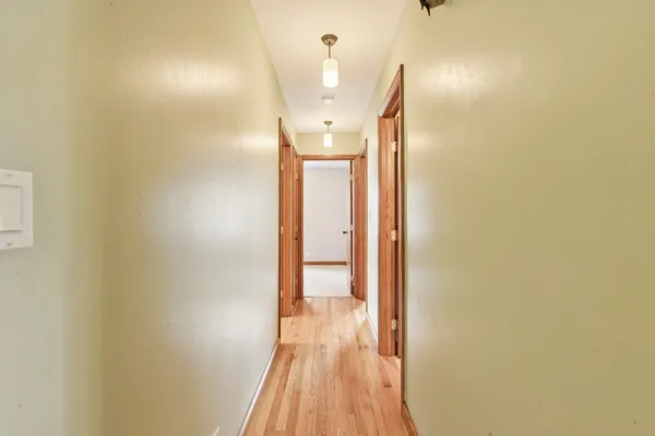 a view of a hallway with wooden floor and a chandelier
