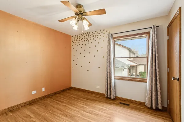 an empty room with wooden floor closet and windows