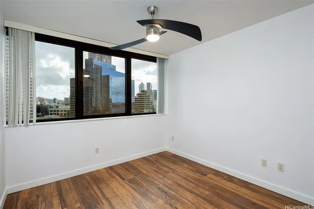 a view of empty room with wooden floor and fan
