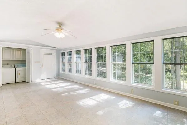 a view of an empty room with a window and a kitchen