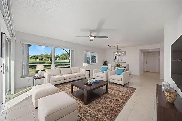 an empty room with chandelier fan and windows