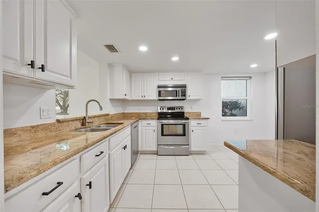 a kitchen with granite countertop white cabinets and a sink
