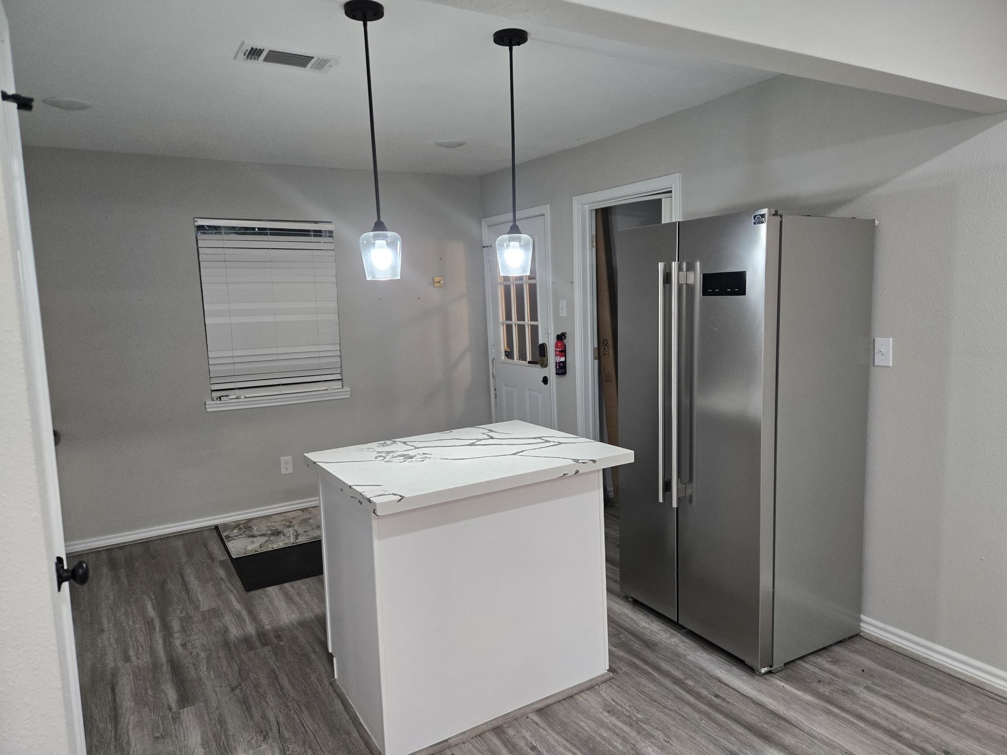 3102 Friar Point Road Houston, TX 77051 - Photo 3 of 11 Sleek kitchen featuring stainless appliances, prep island, and wood-look flooring.