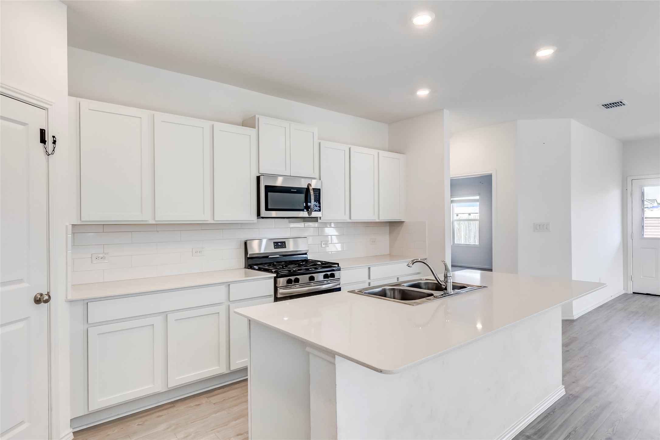 591 Avre Loop Kyle, TX 78640 - Photo 12 of 34 a kitchen with white cabinets stainless steel appliances and wooden floor