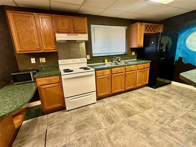 a kitchen with stainless steel appliances granite countertop a sink a stove and a refrigerator