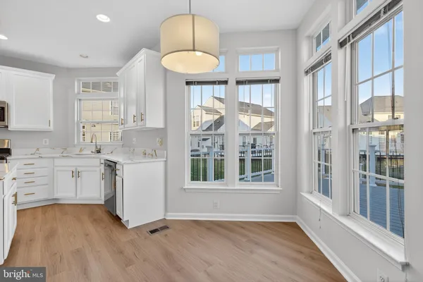 a kitchen with white cabinets and wooden floors