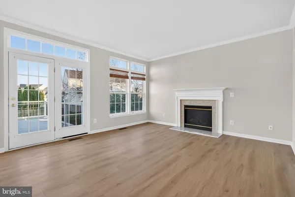 an empty room with wooden floor fireplace and windows