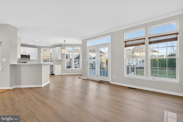 a view of an empty room with wooden floor and a kitchen