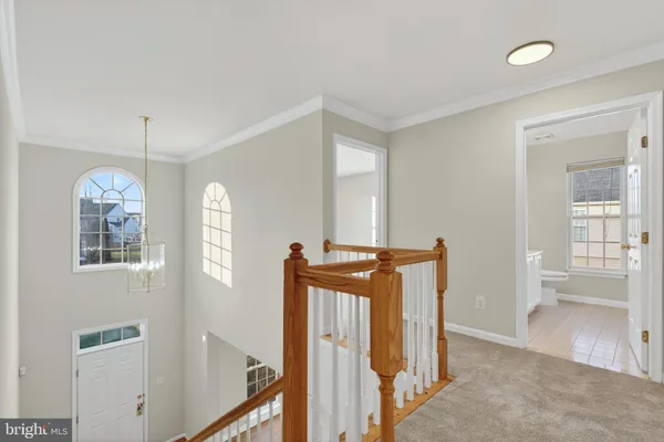 a view of a hallway with windows and chandelier