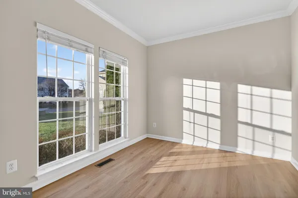 a view of an empty room with wooden floor and windows