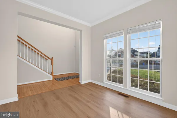 a view of an empty room with wooden floor and windows