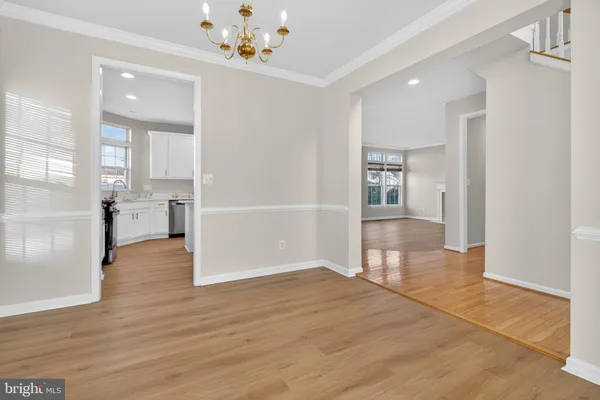a view of empty room with wooden floor and kitchen view