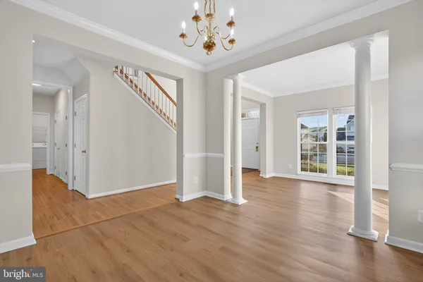 an empty room with wooden floor chandelier and windows