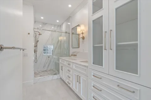 a bathroom with a double vanity sink a toilet a mirror and shower