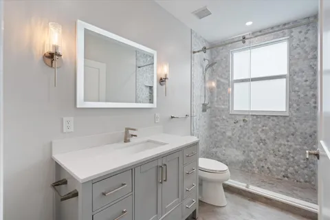 a bathroom with a sink toilet double vanity and shower