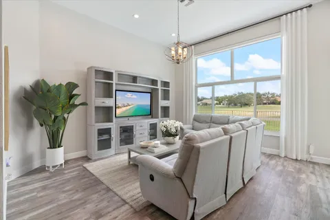 a living room with furniture a large window and a wooden floor