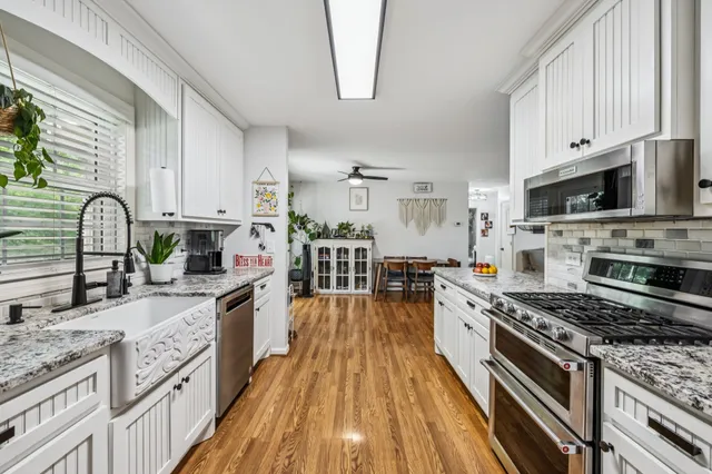 a kitchen with stainless steel appliances granite countertop a sink a stove and a wooden cabinets