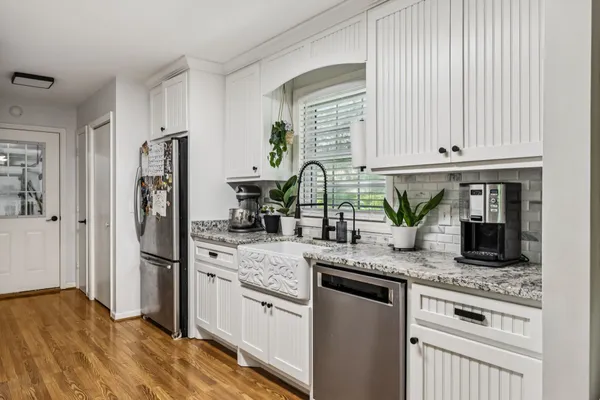 a kitchen with stainless steel appliances granite countertop a stove a sink dishwasher and cabinets with wooden floor