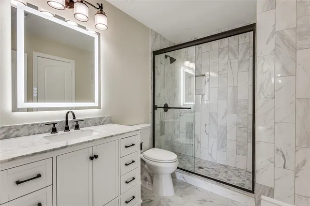 a bathroom with a granite countertop sink toilet a mirror and shower