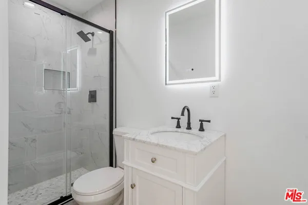 a bathroom with a sink vanity granite toilet and shower