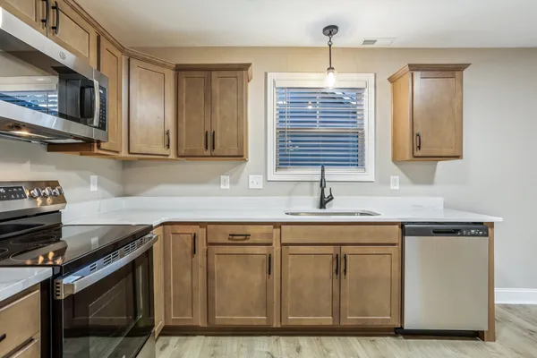 a kitchen with granite countertop a sink cabinets and stainless steel appliances