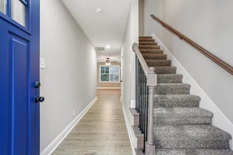 a view of staircase with wooden floor and lots of frames on wall