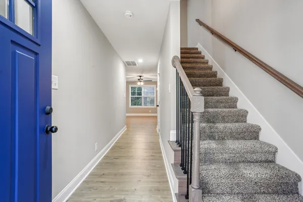 a view of staircase with wooden floor and lots of frames on wall
