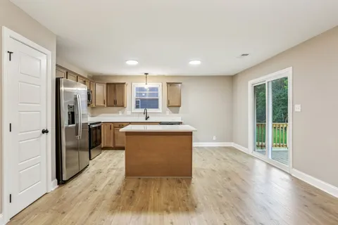 a kitchen with kitchen island wooden floors appliances and cabinets