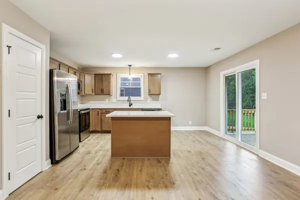 a kitchen with kitchen island wooden floors appliances and cabinets