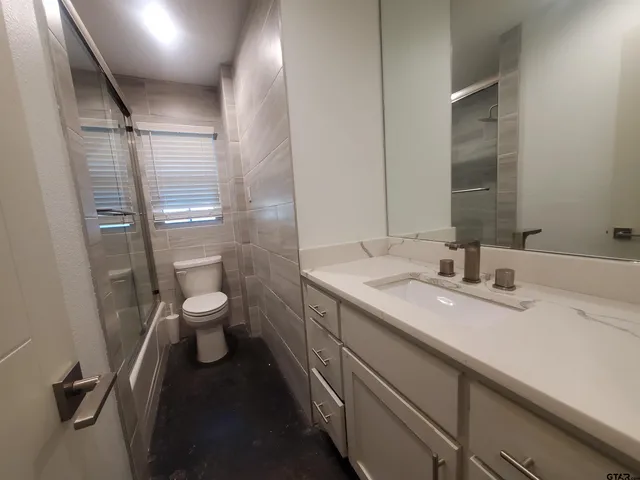 a bathroom with a granite countertop sink toilet and shower