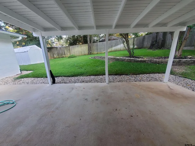 a view of a backyard with table and chairs plants and a barbeque