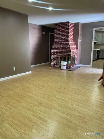 a view of an empty room with wooden floor and a fireplace