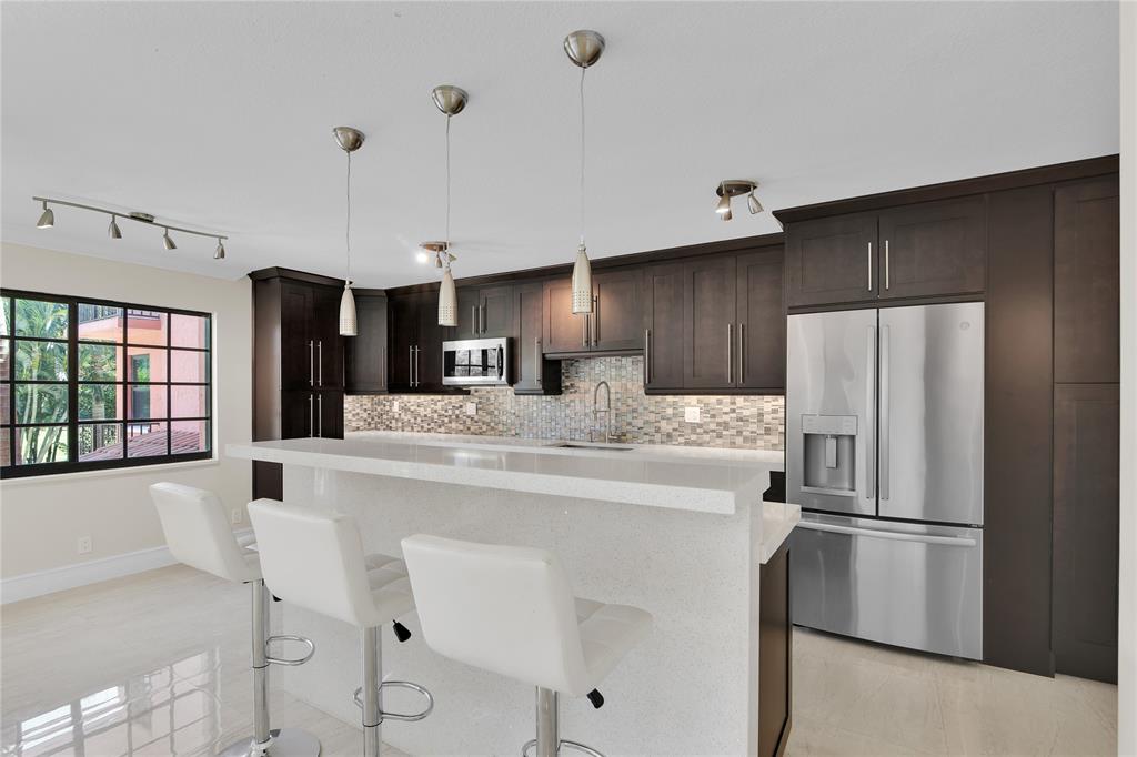 250 East Royal Palm Road, Unit 2A Boca Raton, FL 33432 - Photo 6 of 26 a kitchen with kitchen island a refrigerator a stove a dining table and chairs with wooden floor