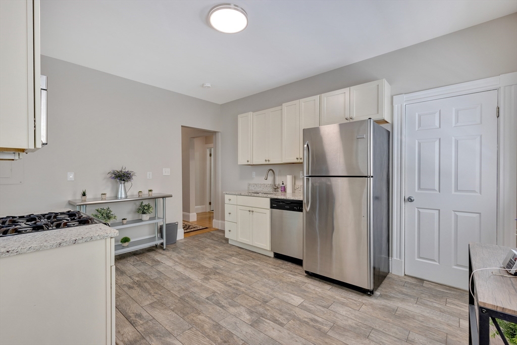 24 Bentley Street, Unit 1 Boston, MA 02135 - Photo 11 of 21 a kitchen with a refrigerator a stove and white cabinets