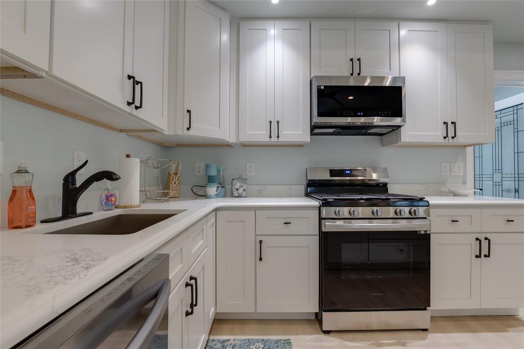 448 Locklie Street Dunedin, FL 34698 - Photo 15 of 51 a kitchen with stainless steel appliances granite countertop a sink a stove a microwave and cabinets