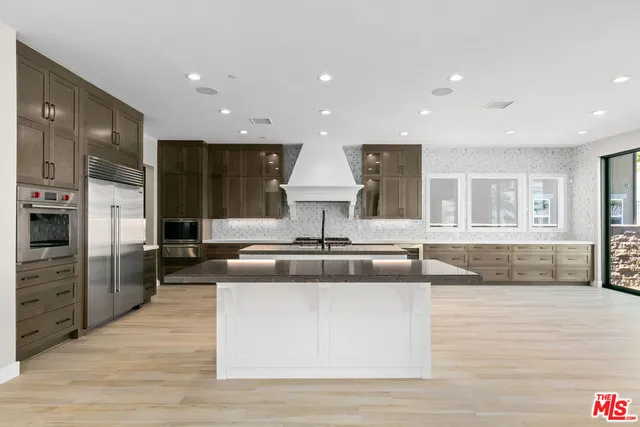 a kitchen with stainless steel appliances granite countertop a sink a counter top space and living room view