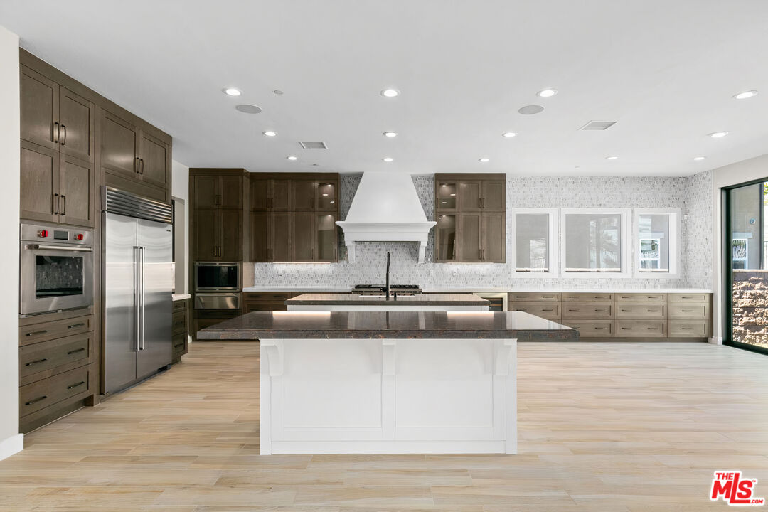 20517 Deer Grass Court Porter Ranch, CA 91326 - Photo 20 of 75 a large kitchen with stainless steel appliances granite countertop a large counter top and a wooden floor