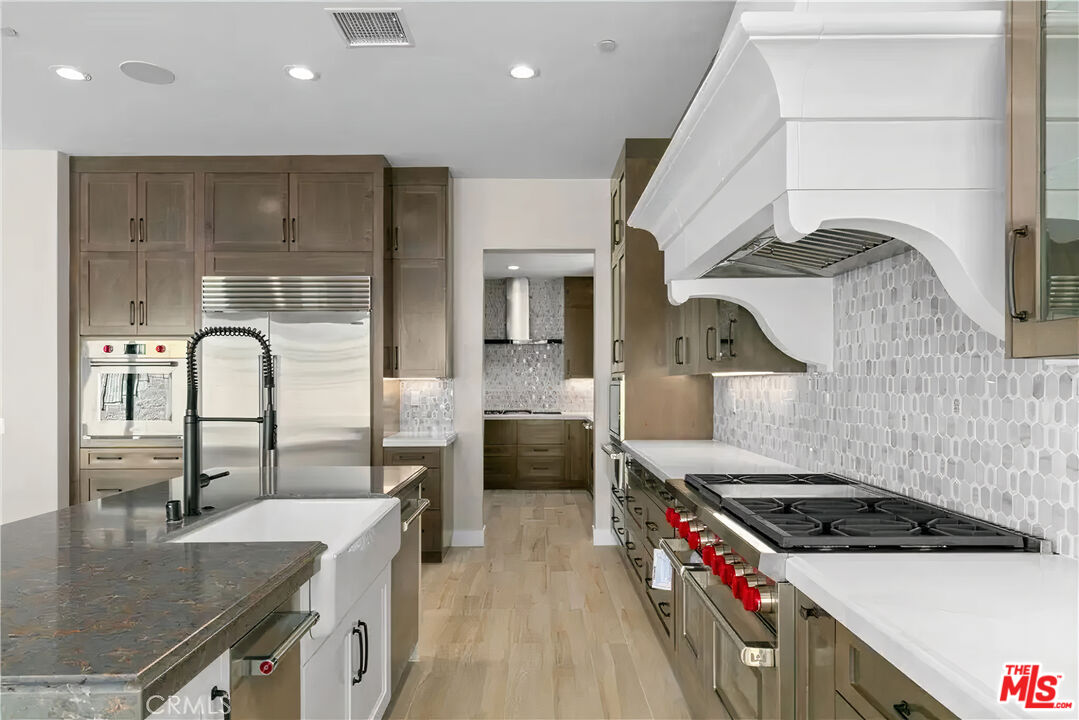 20517 Deer Grass Court Porter Ranch, CA 91326 - Photo 31 of 75 a kitchen with stainless steel appliances granite countertop a sink stove and cabinets
