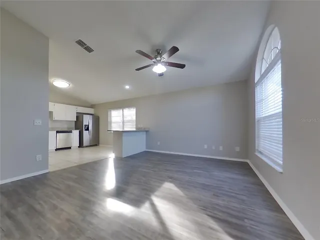 a view of an empty room with window and wooden floor