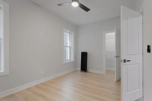 a view of empty room with wooden floor and fan