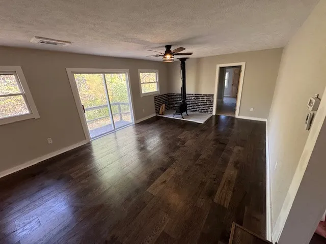 an empty room with wooden floor fan and windows